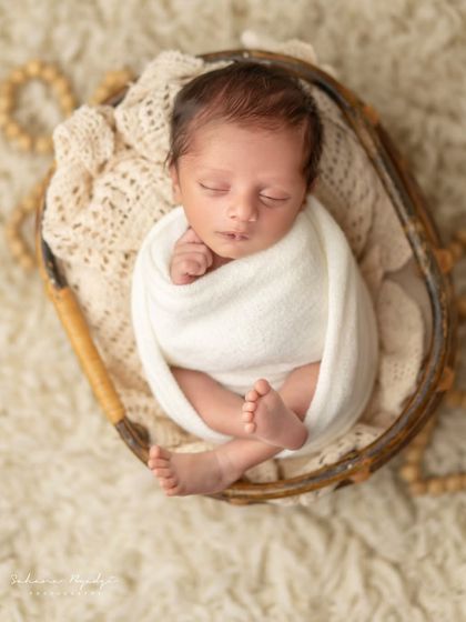 A tiny treasure in a basket. This overhead shot shows a newborn snugly wrapped, a classic and beloved pose.