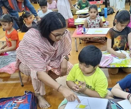 A teacher helps a young student with his drawing. This personal attention is at the heart of my teaching philosophy.