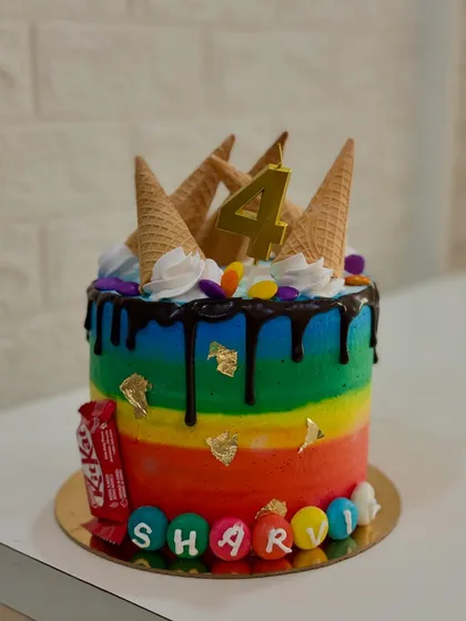 A side view of the rainbow cake, highlighting the colorful striped layers of buttercream.