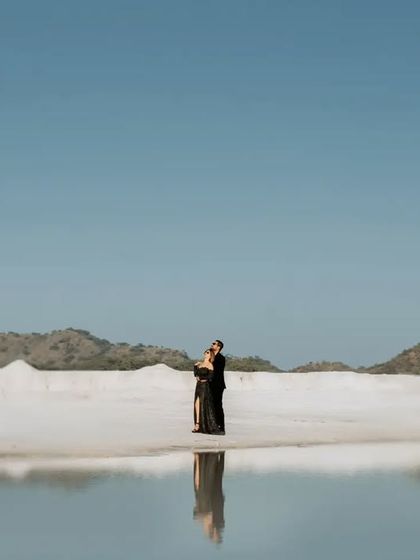 A minimalist shot of the couple reflected in the water, creating a serene and beautiful image that emphasizes their connection in the vast landscape.