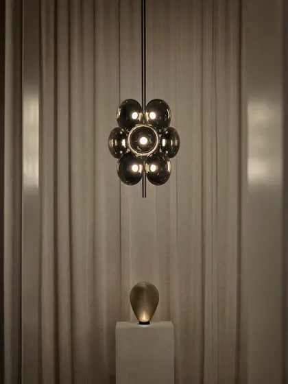 The Aeris light, inspired by the ethereal beauty of clouds. This fixture embodies softness and lightness through the repetition of sculptural, smoked glass forms, creating an ethereal centerpiece.
