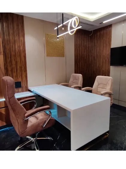 An angled view of Mr. Siraj's cabin, showing the clean lines of the white marble desk against the dark, polished floor and wood-paneled walls. The lighting is designed to be both functional and atmospheric.