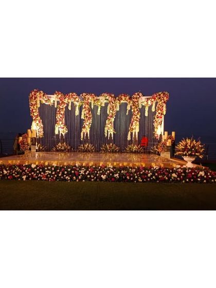 A supreme reception stage set against the evening sky and water. The intricate structure is adorned with cascading florals and crystal elements, creating a breathtaking focal point for the celebration.