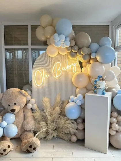 A beautiful and clean teddy bear theme with an "Oh Baby" neon sign. The decor uses a soft blue and beige palette with pampas grass, perfect for a modern baby boy shower.