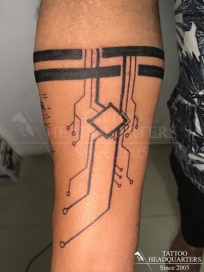 A tech-inspired armband tattoo designed to look like a circuit board, a unique and modern take on the classic band.