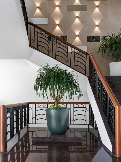 The entrance to The High-Flying Office features a transformed double-height lobby with new granite flooring and a feature wall with up-and-down lighting on the staircase.