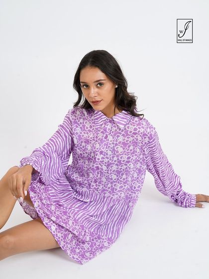 A seated pose showcasing a purple patterned dress, ideal for showing how the fabric drapes.
