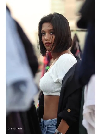 A close-up portrait with a focus on the model's expression and the clean lines of her outfit.