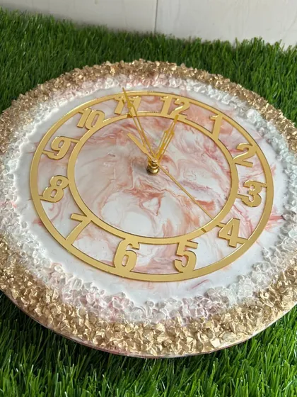 A luxurious clock with a pink and white marble center and a full, textured border of gold and white crystals.