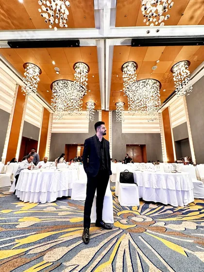 A wide shot showcasing the grand ballroom and my all-black corporate event attire. Sharp, professional, and ready for the stage.