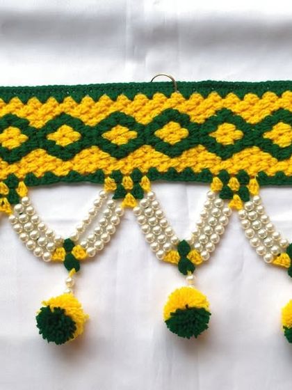 A beautiful geometric pattern toran in yellow and green, finished with pearl strings and matching pom-poms.