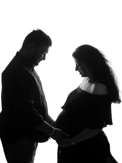 A classic black and white silhouette of an expecting couple. This artistic style focuses on the beautiful shape of the baby bump and the connection between the parents-to-be.