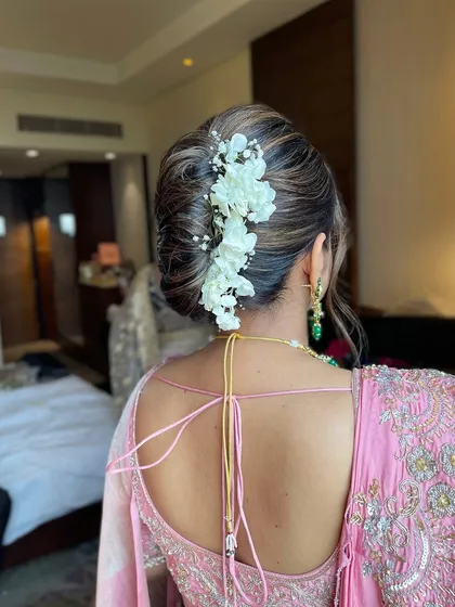 A close up of the floral updo for a wedding guest, showing the detail of the interwoven hair and the placement of the white flowers and baby's breath.