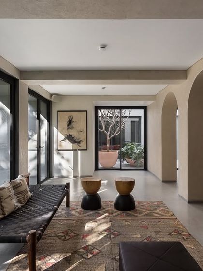 A view from the dining area into a sunlit courtyard, illustrating our principle of integrating nature into every part of the home. The arched openings create a graceful transition between the spaces.