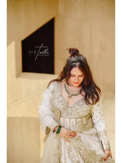 A quiet, downward glance from the bride. This pose highlights her intricate necklace and the detailed work on her outfit, creating a soft and elegant portrait.