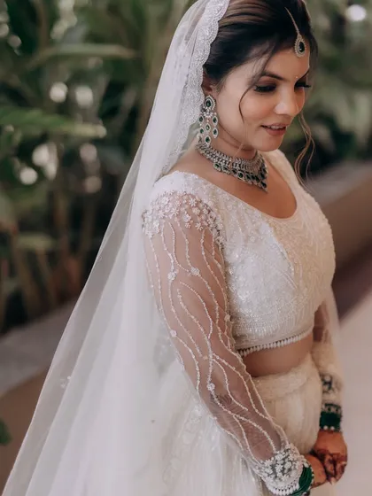 A portrait of the bride in her white lehenga, her veil adding a touch of romance. The soft glam makeup is perfect for this modern bridal style.