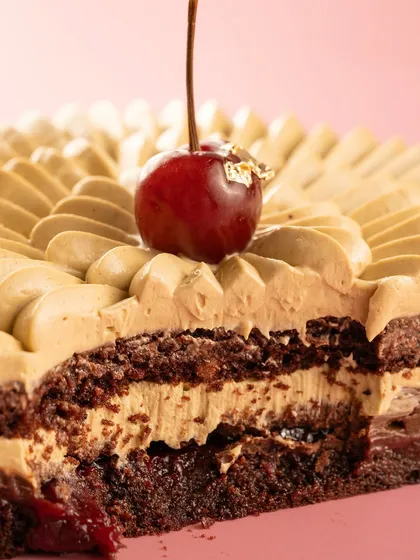 A cross-section of a black forest cake, revealing the layers of cream, chocolate, and cherry. The close-up highlights the rich texture.