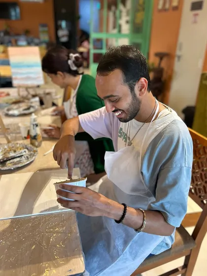 A participant enjoying the process, smiling as he mixes materials for his textured painting. We believe the journey of creating is just as important as the final piece.