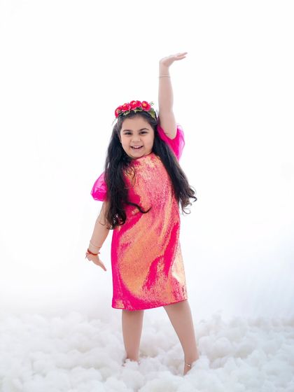 A joyful, energetic pose from this little girl, reaching for the sky amidst a cloud of white fluff.