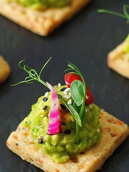 Our canapés are perfect for any gathering. This one features our smashed avocado on a crisp cracker, a simple yet elegant bite for your weekend parties.