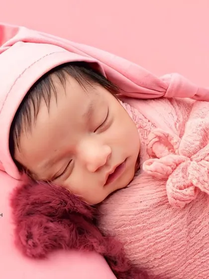 A close-up portrait of the baby in their pink sleepy hat, looking utterly peaceful.
