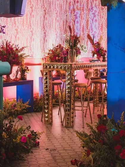 The combination of a striking blue console table, a gold bar, and lush florals creates a rich, multi-layered look that is both contemporary and opulent.