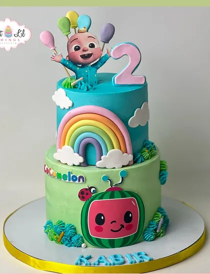 A two-tiered Cocomelon cake for a 2nd birthday. This colorful creation features JJ, a rainbow, and the iconic watermelon, bringing the cheerful show to life.