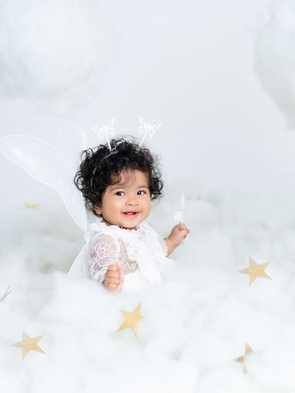 A happy angel playing with a star in her cloud kingdom. This shot captures the playful side of our dreamy, heaven-themed sitter sessions.