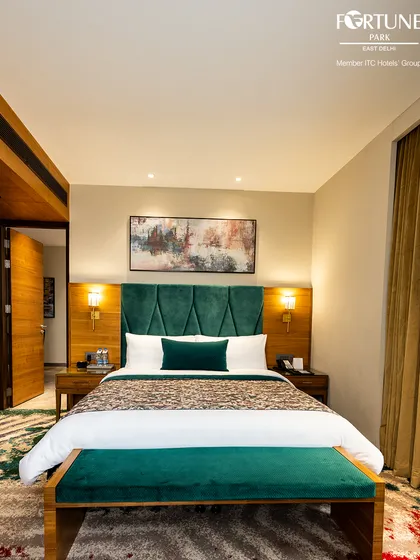 This is our deluxe room, featuring a plush, king-sized bed with an elegant emerald green headboard. It’s a space designed for deep rest and rejuvenation after a day in the city.