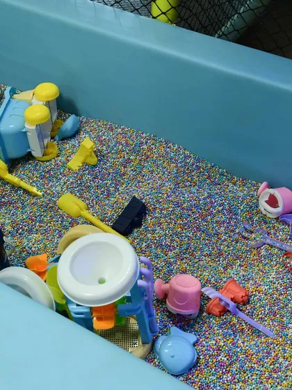 A close-up of our unique sensory pit. It provides all the fun of a sandbox without the mess, filled with colorful grains and beach-style toys.