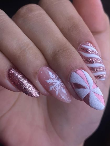 Getting into the festive spirit with this winter-themed set. It includes rose gold glitter, a delicate white snowflake design, and a nail that looks like a perfectly wrapped pink present.