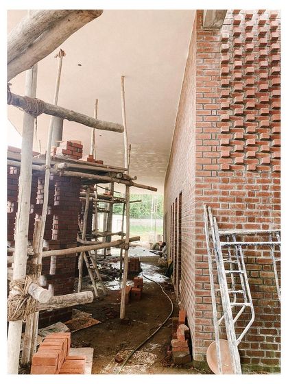 A close-up of the textured brickwork on the auditorium facade under construction. The protruding bricks create a dynamic pattern of light and shadow that changes throughout the day.
