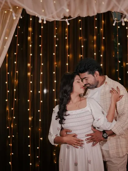 An intimate embrace in front of a curtain of lights, creating a cozy and romantic atmosphere.