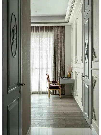 This view down the master bedroom passage highlights the separate doors for the 'his' and 'hers' walk-in closets, each marked with custom initials. This design leaves the main bedroom area clean and clutter-free.