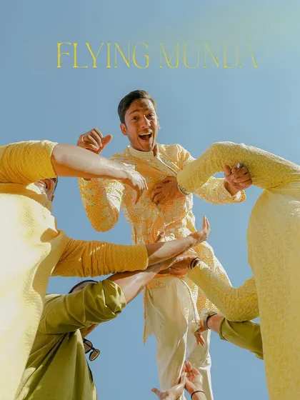 The groom is lifted into the air by his friends, a classic "Flying Munda" shot full of energy and excitement.