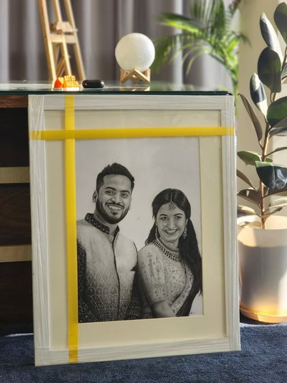 The framed couple portrait in my studio, with soft lighting highlighting the textures of the drawing.