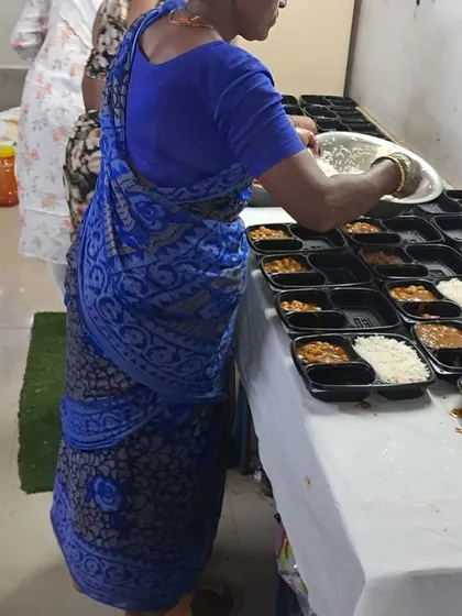 Our team members filling compartmentalized thali boxes for the St. Xavier's College lunch. Each component is added carefully.