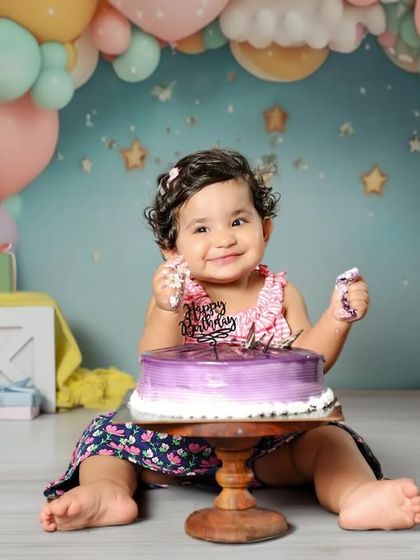 She is so happy with her purple birthday cake! I love capturing the pure joy on their faces during a cake smash session. 😍