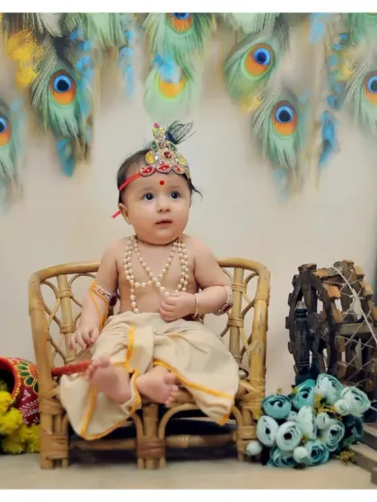 This baby Krishna pose with a miniature spinning wheel and peacock feather backdrop is one of our most requested setups for Janmashtami shoots.