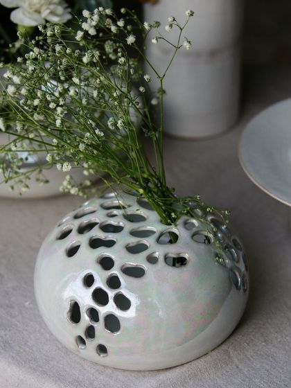 A unique perforated flower vase from the 'Celebrations' collection, with a beautiful mother of pearl glaze that catches the light.