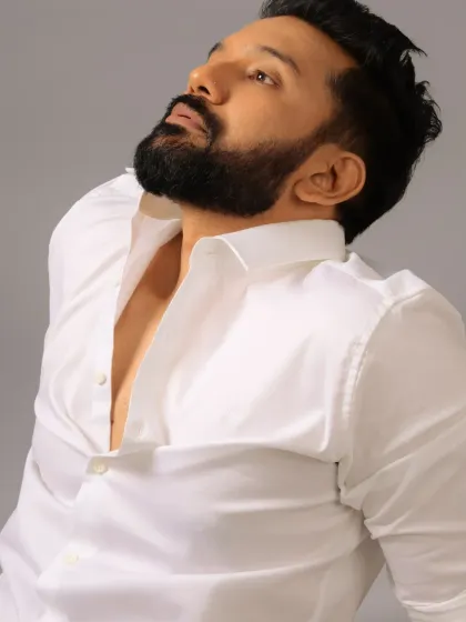 A dramatic, upward-looking pose. The grooming ensures that even with strong lighting, the skin looks smooth and the features are well-defined.