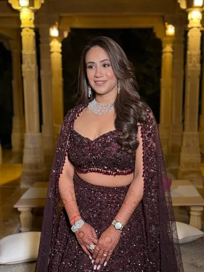 A full-length shot in a stunning architectural setting. The deep color of her lehenga and the sparkling makeup create a dramatic and memorable look.