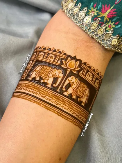 A detailed close-up of an elephant cuff design on the arm, showing the intricate patterns on the elephants and the lotus flower between them.
