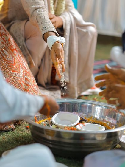 A close-up detail shot of the rituals being performed, focusing on the hands and the offerings.