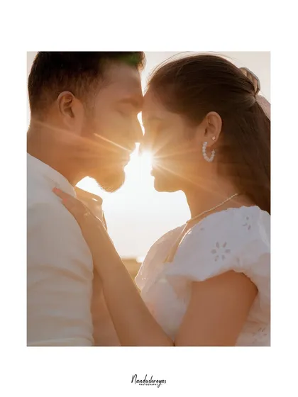 A beautiful silhouette of a couple against a bright sun flare, creating an artistic and romantic portrait.