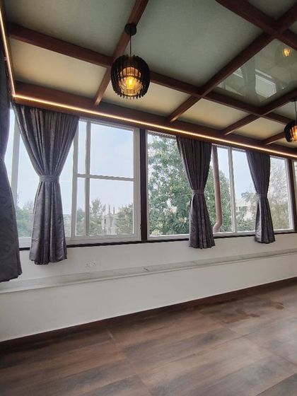 An elegant and functional indoor space created with a glass pergola roof. The combination of large windows, a transparent roof, and rich wood flooring makes the room feel bright, airy, and connected to the outdoors.