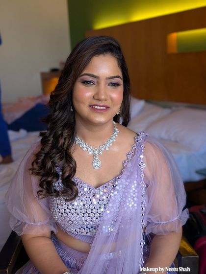 A flawless party look in a lovely lilac shade. The makeup is soft and shimmery, with a focus on glowing skin and beautifully styled curls.