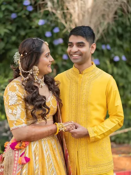 A collection from a beautiful Haldi ceremony. The bride's makeup is fresh and minimal, with a pop of color on the lips. Her hair is styled in a half-up, half-down look with braids, perfect for the fun and vibrant event.