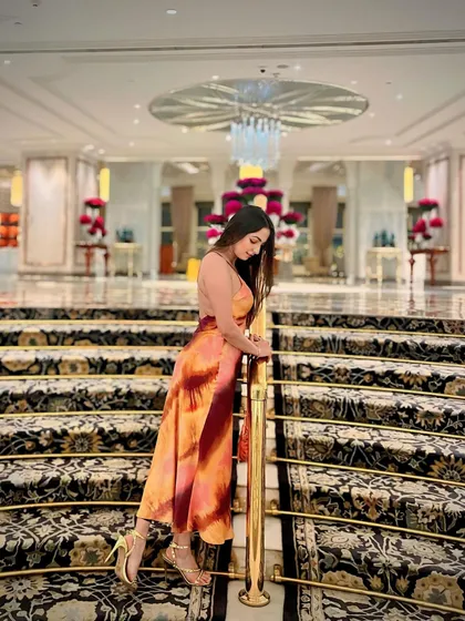 Posing on the grand, carpeted staircase of a luxury hotel lobby. This shot highlights the opulence and scale of the property's interiors.
