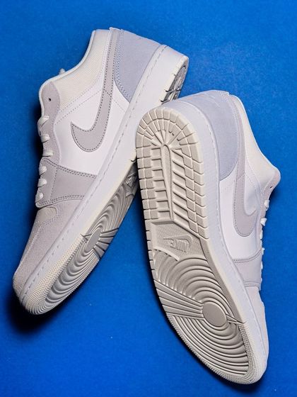 An overhead shot of the Jordan 1 Low 'Paris', displaying the clean white and light grey colorway and the unique sole pattern.